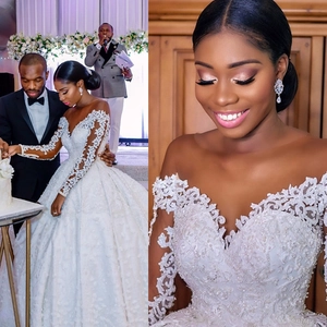 Detail of V-neck white lace wedding dress with intricate pearl embroidery and long sleeves