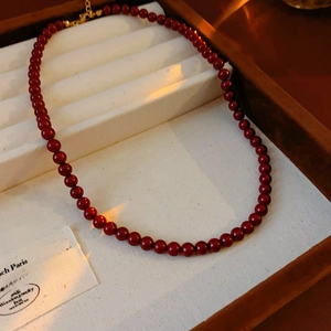 Detail of deep red beaded titanium steel necklace in a velvet jewelry display box