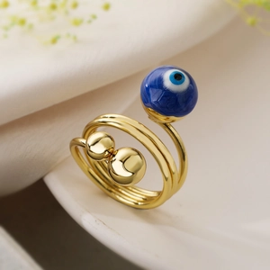 Close-up of gold-plated multi-layer ring with blue evil eye bead and smooth metal sphere