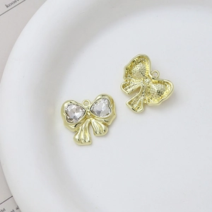 Detailed close-up of bow-shaped golden pendants with heart-shaped crystals on white plate