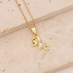 Detailed view of a gold bear pendant with clear cubic zirconia and black eye accents