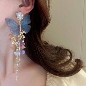 Detail of long tassel earrings with blue mesh butterfly and golden leaf charms
