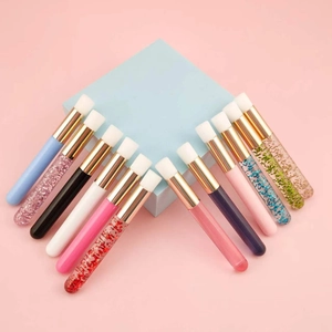 Detailed view of 14 colorful eyelash cleaning brushes with glitter handles on pink background