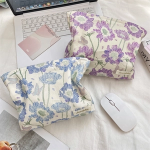 Floral cotton cosmetic bags with daisy prints next to a laptop on a white desk
