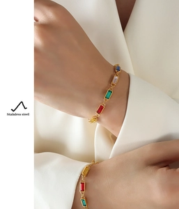 Detailed view of colorful zircon gold bracelet in stainless steel on a white blazer