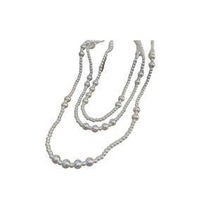 Elegant multi-layered pearl necklace with alternating sizes on a minimalist background