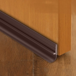Detailed view of flexible brown rubber door bottom seal installed on a wooden door