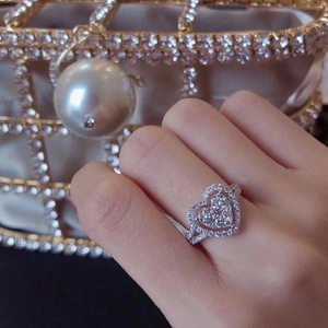 Close-up of sparkling heart-shaped ring set with brilliant pavé stones on finger