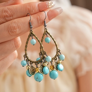 Detailed close-up of ethnic bamboo style bronze drop earrings with blue turquoise beads