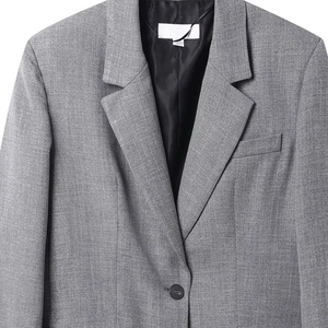 Detail of light gray single-button blazer showing premium wool fabric texture and notched lapel