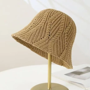 Khaki knit bucket hat with hollow cable stitch pattern on a gold display stand