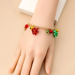 Close-up of model wearing a gold Christmas bracelet with colorful bells and bow charms