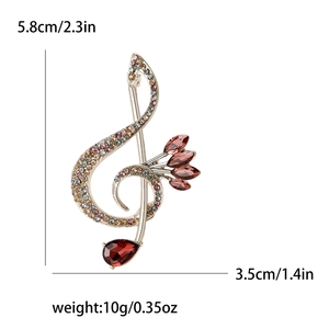 Golden musical treble clef brooch with colorful crystals and red teardrop gemstone detail