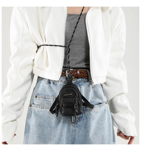 Close-up of mini black crossbody bag with textured material and woven strap for girls