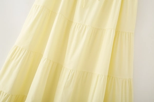 Close-up of tiered layered stitching and smooth fabric texture on light yellow skirt