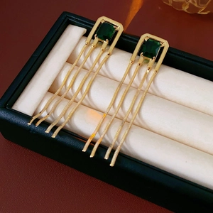 Close-up of vintage gold tassel earrings with square emerald stones in a jewelry box