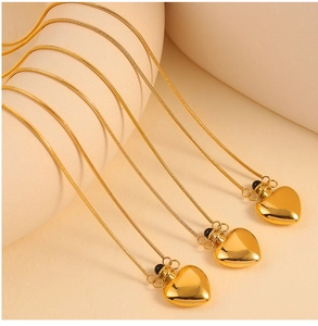 Close-up of three 18K gold-plated heart pendant necklaces with sleek snake chain texture