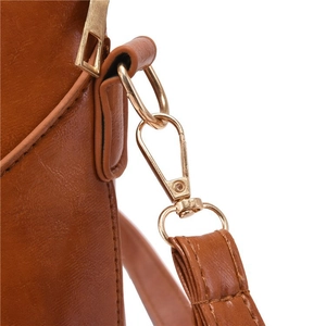 Detailed view of golden metal hook hardware on brown leather tote bag strap