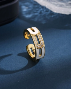Detail of a golden open ring featuring white enamel finish and sparkling crystal inlay