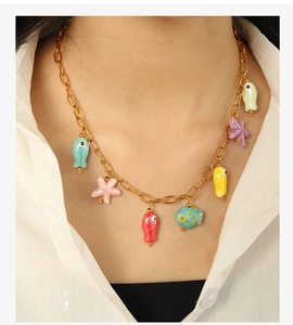 Detail of colorful ceramic ocean charms like fish and starfish on a golden chain