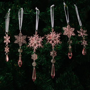 Detailed view of pink acrylic snowflake ornaments hanging on a festive Christmas tree branch