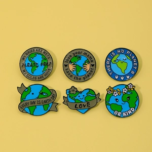 Flat lay of six cartoon enamel pins with earth day and eco-friendly slogans on yellow background