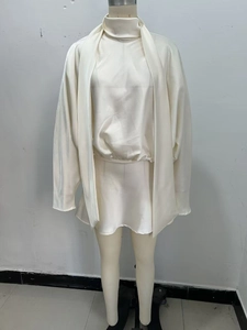 Detail of white satin two-piece dress showing high neck top and mini skirt texture