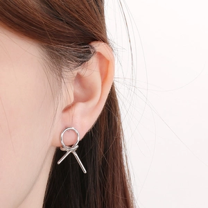 Close-up of minimalist silver knot hollow geometric stud earring worn on model ear