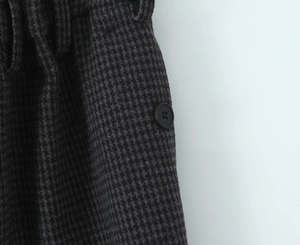 Macro shot of dark grey houndstooth wool fabric texture with black round button detail