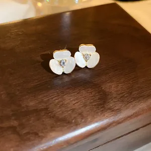 Vue macro de boucles d'oreilles fleur en perle avec bordure dorée et cristal sur bois