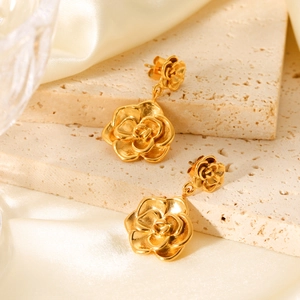 Detail of 18K gold stainless steel rose earrings on stone and silk background