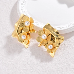 Elegant gold flower tassel earrings with white pearls on a vintage ceramic plate