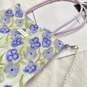 Dettaglio della borsa floreale con motivi a fiori viola e catena di perle bianche