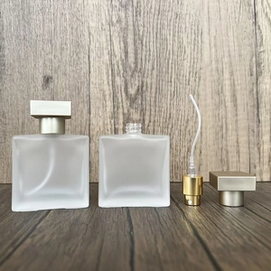 Close-up of frosted square glass perfume bottles with metallic gold spray pumps