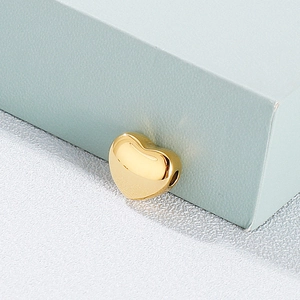 Polished gold heart charm pendant for jewelry making shown on light blue background