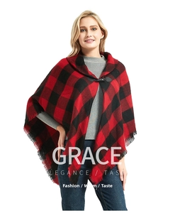Detail of red and black buffalo plaid poncho featuring fringe trim and horn button closure