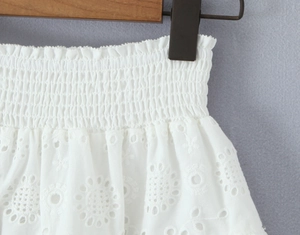 Détail de la jupe en coton blanc avec broderie florale et taille plissée élastique