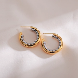 Minimalist C-shaped gold hoop earrings with silver beaded inlay on velvet background