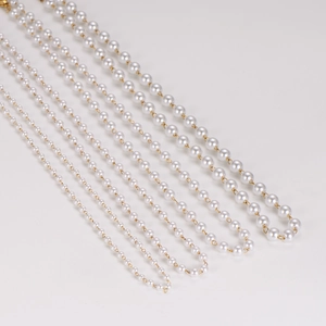 Various sizes of vintage white imitation pearl necklaces with golden metal chains on white