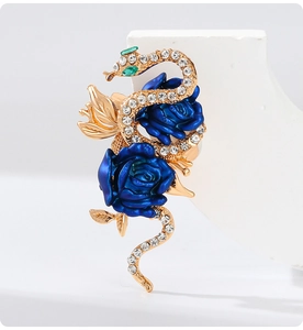 Detailed view of snake brooch with blue roses and sparkling rhinestones on white display