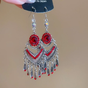 Macro shot of silver bohemian drop earrings with red stones and metallic fringe