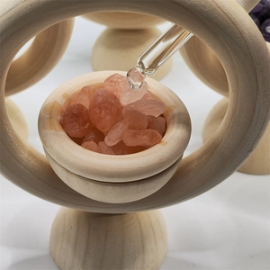 Macro view of essential oil drops on pink salt stones within a round wooden diffuser ring