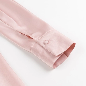 Detailed macro view of pink satin dress sleeve with elegant fabric-wrapped button