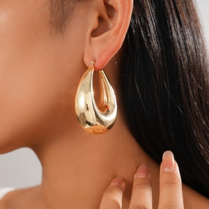 Polished gold teardrop hoop earring close-up on model for a minimalist fashion look