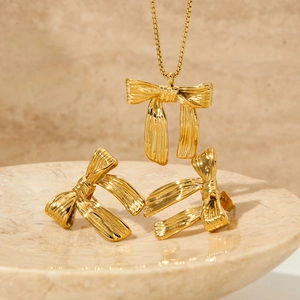 Elegant gold bow necklace and earrings set displayed on a marble tray for a luxury look