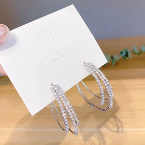 Macro shot of silver triple-hoop earrings featuring densely set sparkling rhinestones