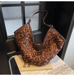 Detail of leopard print tote bag with brown shoulder strap and leather brand label