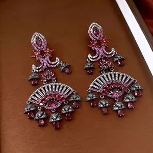 Vintage style drop earrings with red crystals and fan design on a textured display