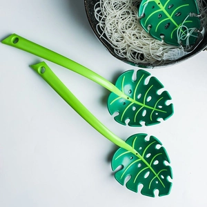 Macro detail of two green monstera leaf slotted spoons used for straining noodles