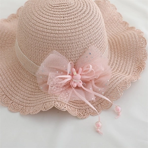 Detailed view of kids' pink straw hat with large mesh bow and cute 3D bunny ornament